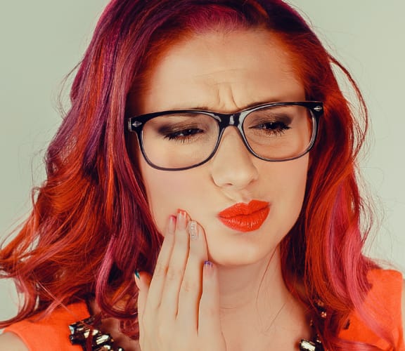Young woman holding her jaw line uncomfortably